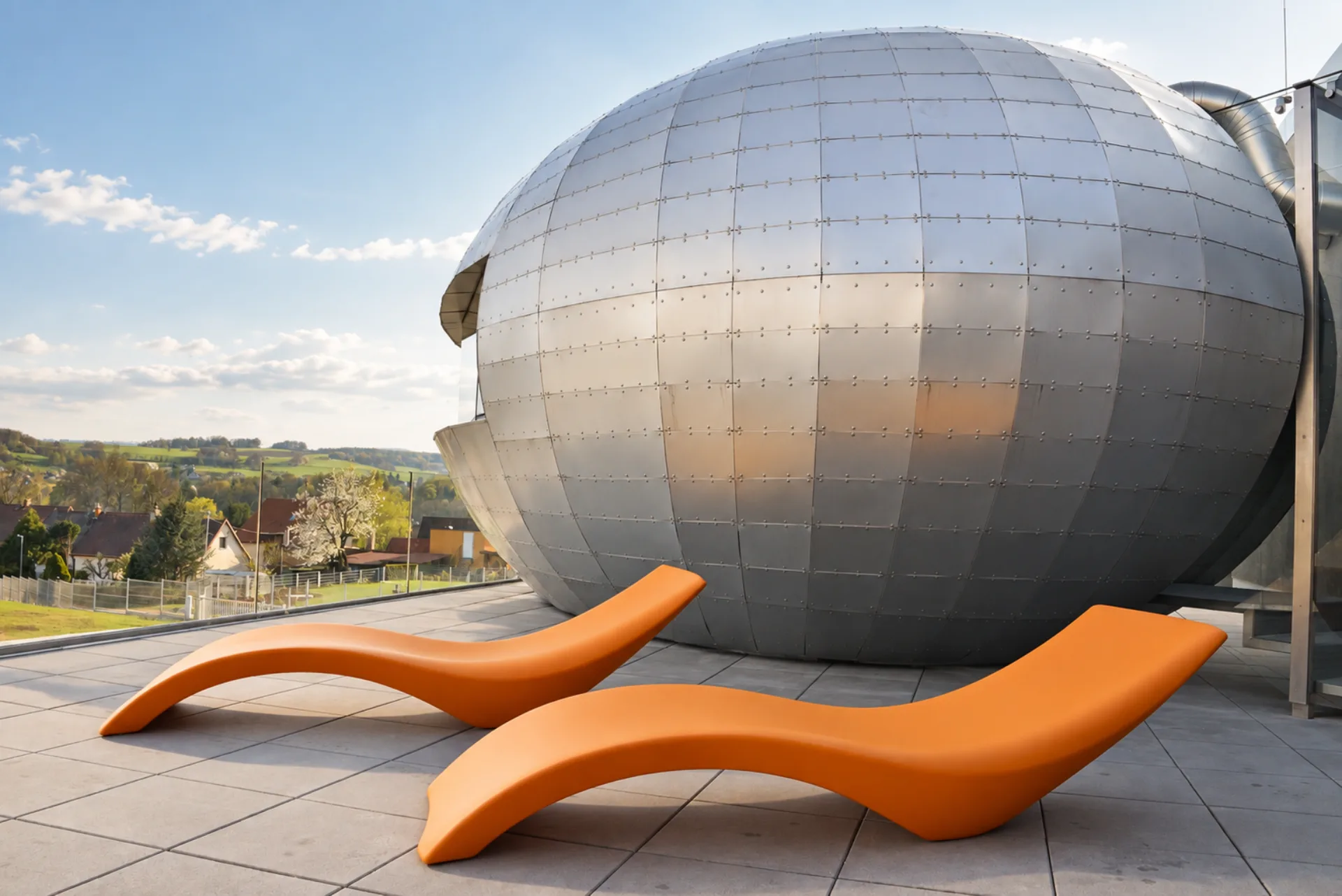 Terasa Hotelu Antonie ve Frýdlantu s výrazným kovovým architektonickým objektem a oranžovými lehátky.