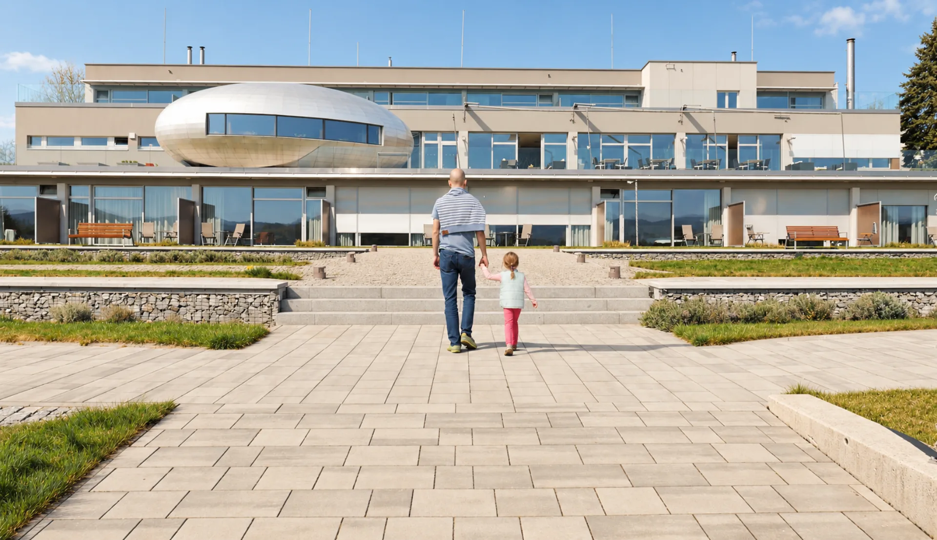 Otec s dcerou přicházejí k Hotelu Antonie ve Frýdlantu před moderní budovou hotelu.