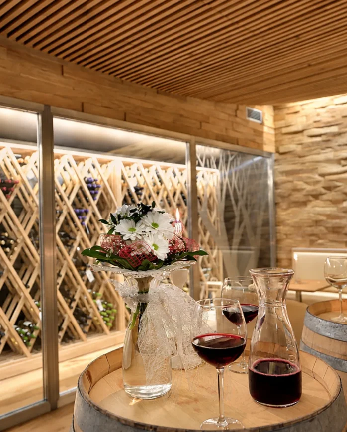 Vinný salonek Hotelu Antonie ve Frýdlantu s archivem vín, sudy a sklenkami červeného vína.
